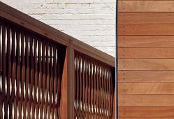 Screen fencing with woven panels and wooden frame in front of white-washed brick wall