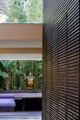 Holzverkleidete Wand mit integriertem Einbauschrank und Buddhakopf auf Fensterablage