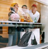 Zwei Frauen und ein Mann machen Pause vom Shopping in einem Café