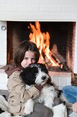 A little girl and a dog in front of a fire