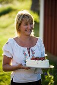 A woman serving a strawberry cake in a garden