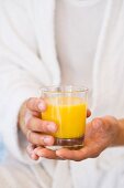 A person holding a glass of orange juice