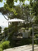 Garden furniture and parasol on wooden terrace in Mediterranean garden