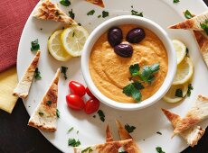A Plate of Hummus and Toasted Pita Bread Triangles; From Above