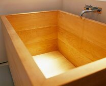 Contemporary wooden bathtub with wall-mounted tap fitting