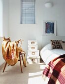 Blanket on chair and stack of boxes next to bed