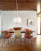 Dining area with wire mesh chairs in dining room with sand-lime brick wall