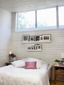 Weisses Schlafzimmer mit eingerahmten Fotos über dem Bett