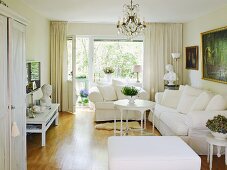 Comfortable sofa and armchair with valance in classic, white living room with large window and balcony door