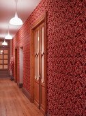 Hall with ornate wallpaper in various shades of red and artificial lighting