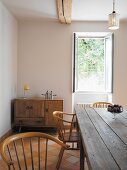Rustic table and wooden chairs in front of open window in dining room