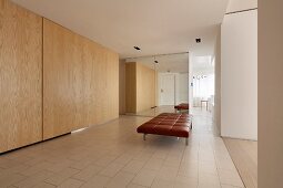 Brown leather couch and fitted cupboards in large, modern foyer