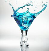 Eiswürfel fällt in ein Glas Blue Martini