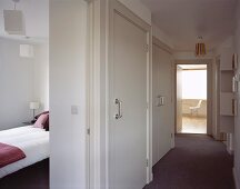 White, modern hall and open bedroom door with view of bed