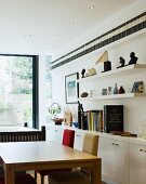 Dining table and chairs in front of white sideboard and shelves
