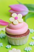 A cupcake with strawberry cream and a yellow sugar flower