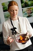 Young woman holding bowl of chicken and pepper stew