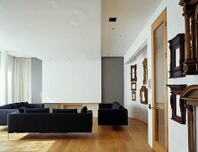 Black sofas and collection of antique picture frames in modern living space