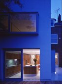 Multi-storey house at twilight with view of illuminated kitchen