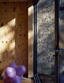 Violetter Hocker aus Kunststoff vor Holzwand und Terrassentür