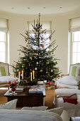 Decorated Christmas tree and armchairs with white upholstery in traditional interior