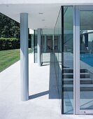 Concrete pillars on terrace in front of long glass wall