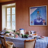 Laid dining table with gingham table cloth in front of wall painted light dusky pink