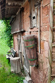 Gartenbank vor alter Ziegelhütte mit an Wand befestigtem Holztrog