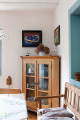 Rustic dining area in front of rustic corner cabinet with glass doors