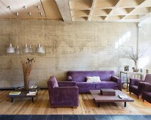 Purple sofa set in living room with concrete wall and wooden floor