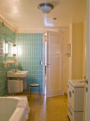 Original 50s bathroom with tiles in baby blue and yellow, steel tube stool and vintage washing machine