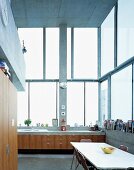 Dining area in kitchen with counter in front of high windows in contemporary house