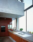 Kitchen counter in front of glass wall beneath floating concrete gallery