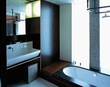 Designtes Bad mit Holzverkleidung an Wand und im Boden eingelassener Badewanne