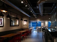 Cafe with long counter and wooden tables with red chairs