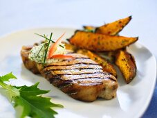 A grilled chop with herb butter and potato wedges