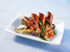 Sausages on a skewer serve with toasted bread and tomato salad