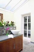 Modern ensuite bathroom with glass roof and plants on washstand with base cabinet