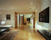 Open-plan living room with modern fireplace, view of floating, wooden staircase and sliding elements in hallway