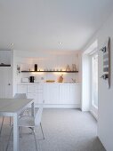 White wooden kitchen in rustic Scandinavian style with 50s chairs and skateboard on wall