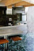 Concrete tops on kitchen unit and dining table, black and white stone tiles and black marbled back wall in modern wooden house