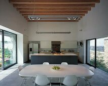 Modern kitchen-dining room with wooden beams on ceiling and large windows on both side walls