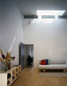 Puristischer Wohnraum mit offenem Sideboard und hellem Sofa unter Oberlicht