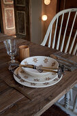 A place setting with stylised edelweiss crockery and mini ski poles on a simple wooden table