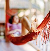 Junge Frau liegt in einer Hängematte auf der Terrasse