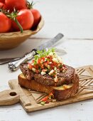 Toasted bread topped with beef steak and tomato salsa