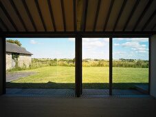 Leerer Wohnraum mit raumhohen Terrassenfenstern und Ausblick