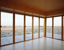 Empty, wood-panelled room with terrace doors and view of landscape