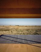 Blick über Holzterrasse auf flache Küstenlandschaft