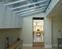 Room in contemporary extension with glass roof and view through open doorway